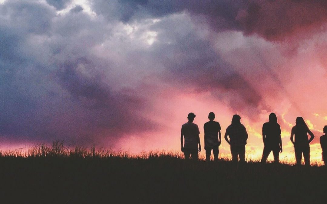 Silhouette of a group of people against a cloudy sunset